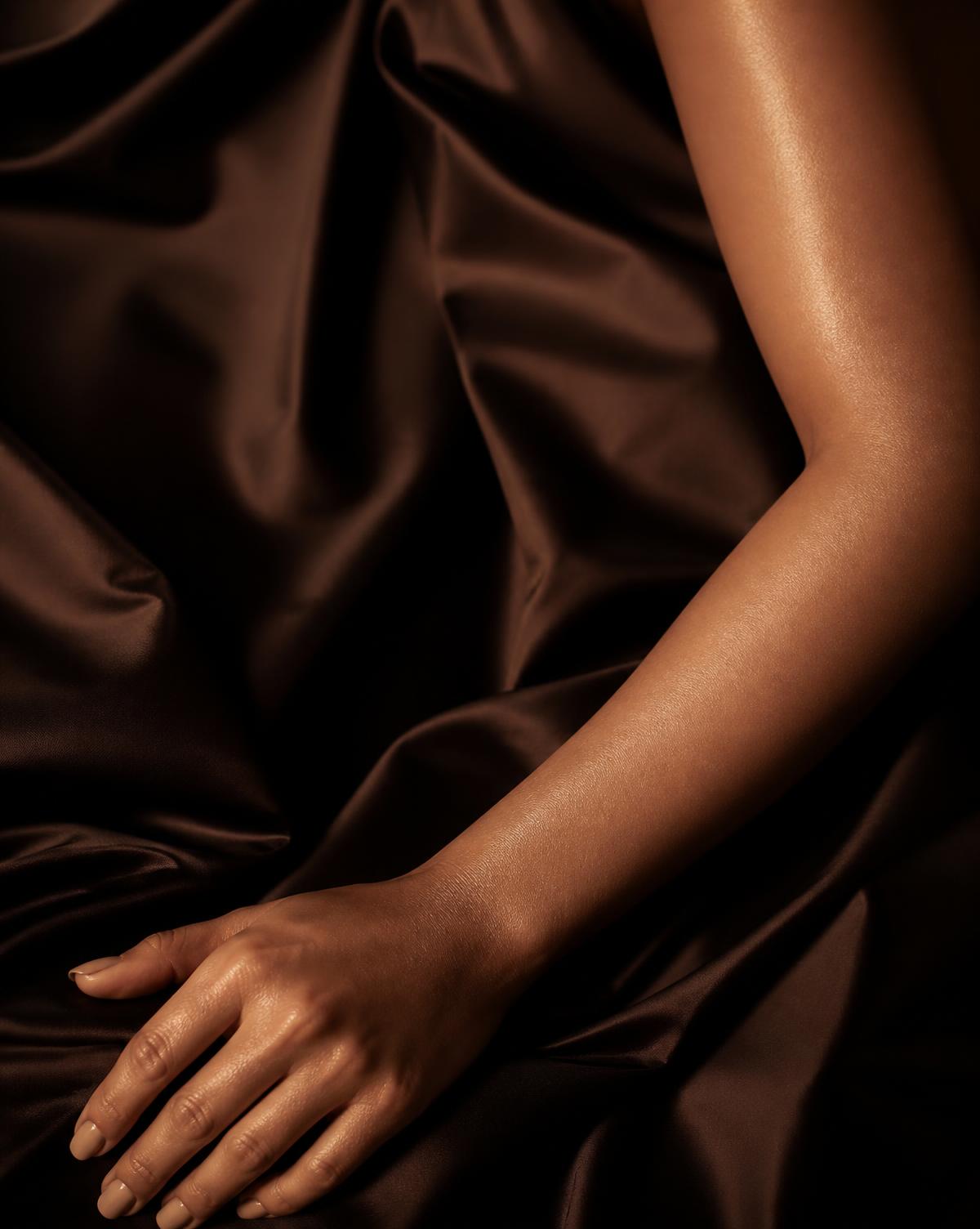 Bronzed skin resting on deep espresso silk